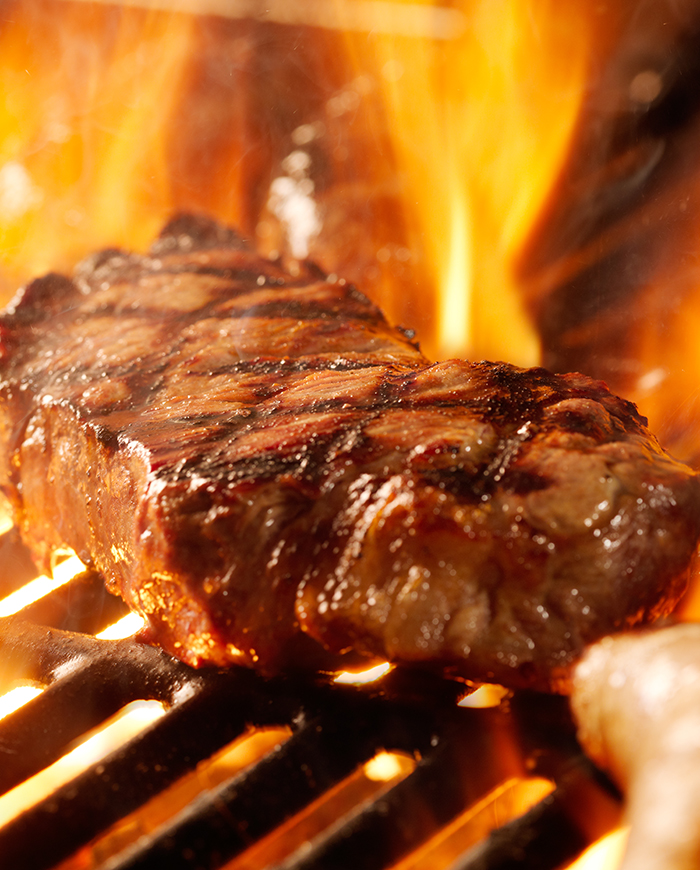 Meat being cooked on a flaming grill