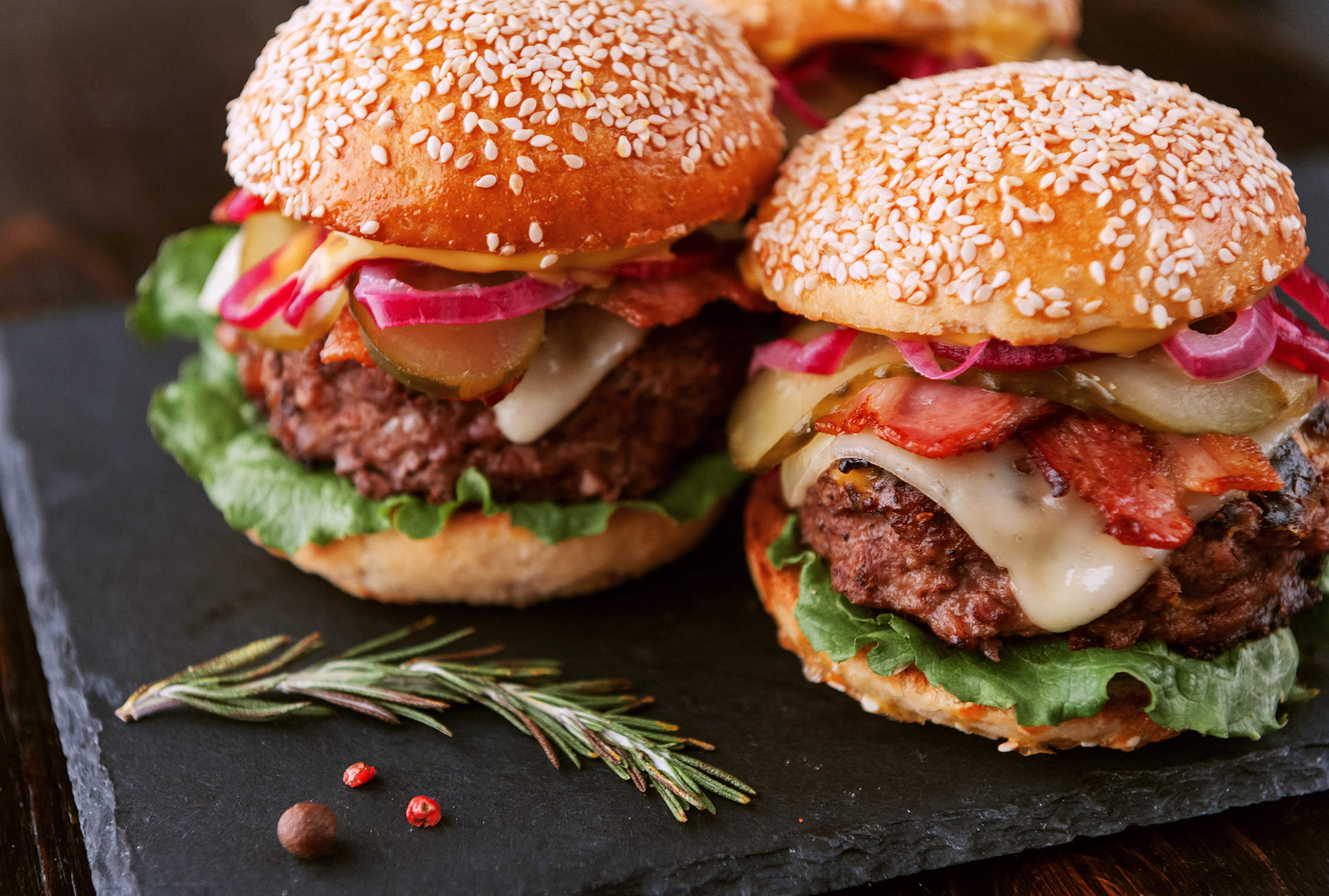 Two burgers on a slate platter