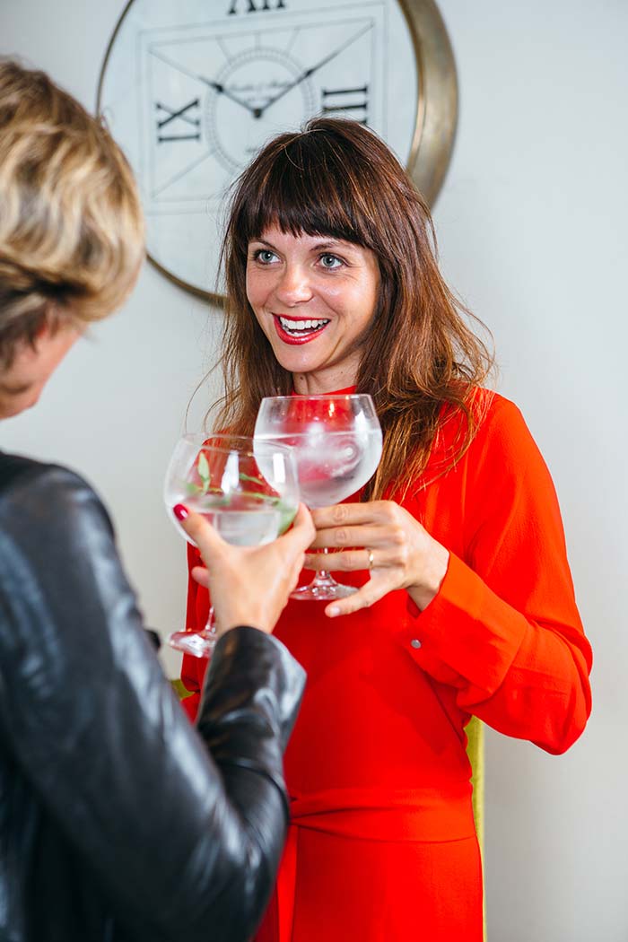 two women holding glasses while chatting