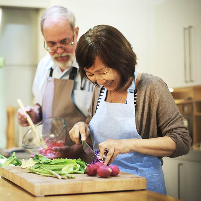 Mature man and woman chopping vegetables